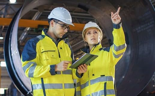 两个机械臂和两个人看着一个产品的制造